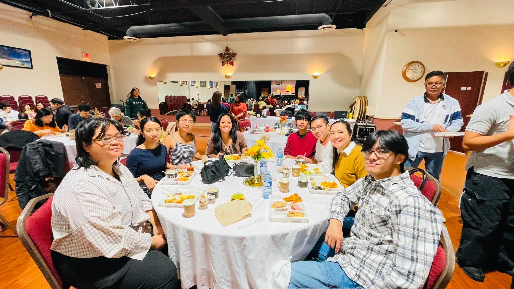 The FCC family seated at tables in the hall for Thanksgiving dinner